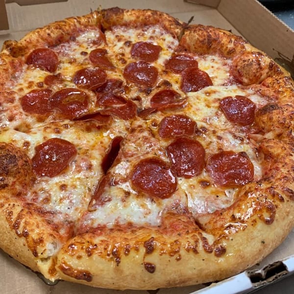 A whole Gumby's pepperoni pizza with melted cheese and a golden crust in a cardboard box.